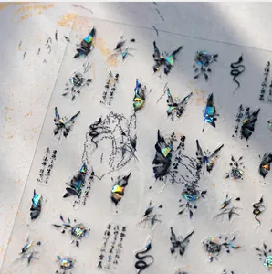 Macro shot of dark art nail stickers with laser gold butterflies and snakes motifs