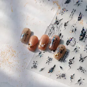 Detail of ink wash nail stickers with butterfly and floral motifs on nude manicured nails