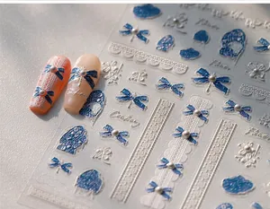 Detailed macro view of 5D embossed nail stickers with blue bows and pearl accents