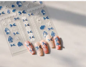 Detail of 3D embossed nail stickers featuring blue denim bows, white flowers and pearls