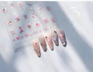 Macro view of 3D nail stickers featuring pink strawberries and ribbons with rhinestones