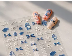Detail of 3D embossed nail stickers featuring blue bows, pearls, and floral lace designs