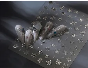 Detailed view of silver metallic snowflake nail stickers on a dark silk background
