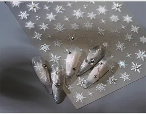 Detailed view of silver snowflake nail stickers and rhinestones on gradient press-on nails