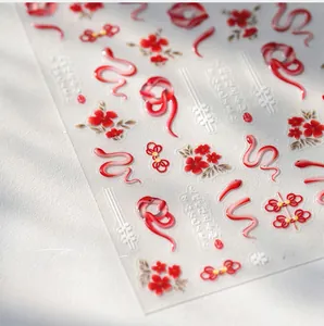 Macro shot of 3D red snake nail stickers with golden floral and Chinese knot patterns