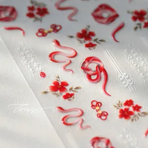 Macro detail of 3D embossed nail art stickers featuring red snakes and Chinese motifs