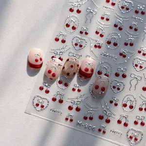 Silver embossed cherry and bow nail art stickers displayed on natural manicured nails