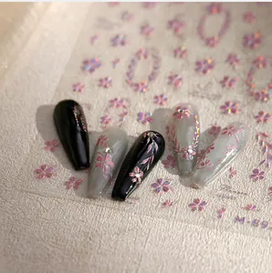 Makroaufnahme von Nagelstickern mit lila Verlaufsblumen und funkelnden Strasssteinen