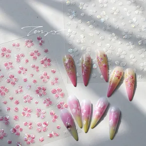 Dettaglio di adesivi 3D per unghie con fiori di ciliegio e texture perlata lucida