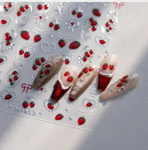 Detail of red cherry and silver bow nail stickers with 3D effect on manicured nails