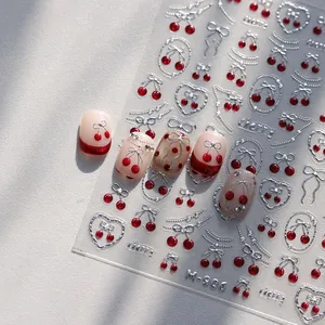 Silver embossed bow and red cherry 3D nail art stickers applied on manicured tips