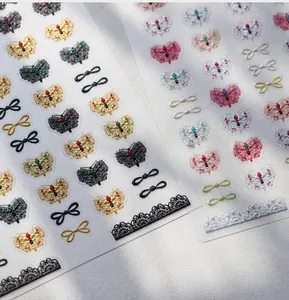 Detail van M-915 nagelstickers met gouden strikjes en kanten bloemmotieven