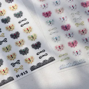 Artistic close-up of M-915 nail stickers with gold bow and butterfly lace patterns