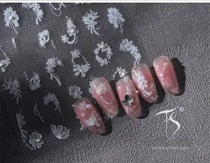 Close-up of white lace flower nail stickers with pearl accents on pink cat-eye nails