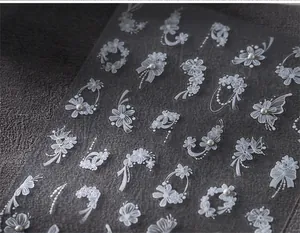 Detailed macro view of 3D white floral nail stickers with pearls and embossed relief