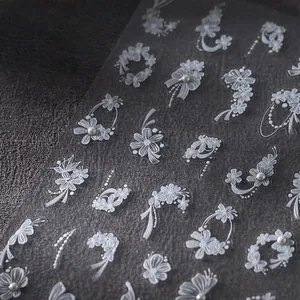 3D white floral lace nail stickers with ribbon bows and pearls on dark background