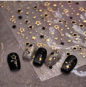 Macro detail of gold and black star nail stickers with cross and dot patterns