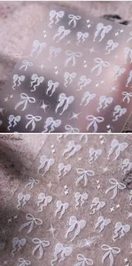 Detail of 5D embossed white bow and sparkle nail art stickers with a translucent matte finish