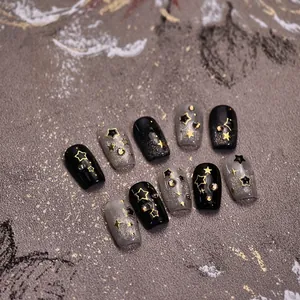 Dark aesthetic press-on nails with black cat eye effect, gold stars, and rhinestones