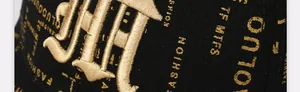 Detail of 3D golden embroidery and fashion prints on a black baseball cap texture