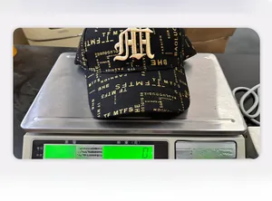 Detailed weighing of the black baseball cap with golden embroidery and monogram pattern