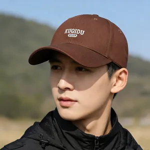 Dark brown baseball cap with white embroidery outdoors on a blurred mountain background