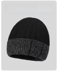 Detail of two-tone knit beanie featuring black fine knit top and grey cable knit cuff