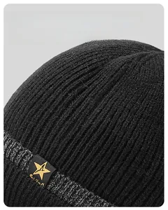 Close-up of thick ribbed knit texture and decorative star badge on a black winter beanie