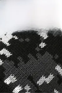 Close-up of knit winter beanie featuring black grey and white geometric patterns