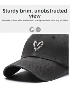 Detailed close-up showing the structured brim and white heart embroidery on the black cotton cap