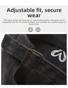 Detail of adjustable bronze buckle and heart embroidery on washed black cotton baseball cap