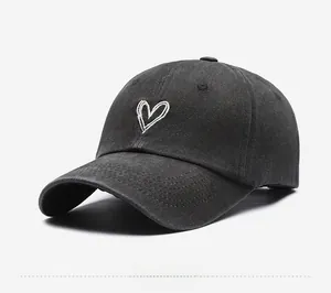 Side view of washed black cotton baseball cap with white heart embroidery detail