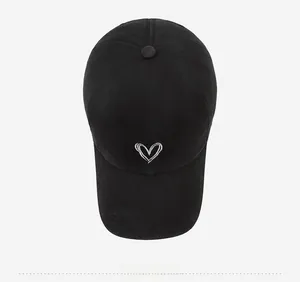 Detailed top-down view of black cotton baseball cap featuring white heart embroidery