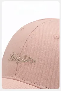 Detailed close-up of premium gold thread embroidery on a pink twill cotton baseball cap