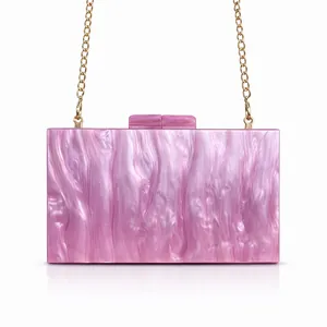 Detail of pink marble acrylic clutch bag with gold chain strap and top metal clasp