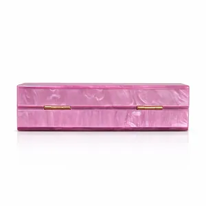 Macro detail of pink pearlescent acrylic evening clutch with gold metal hinges