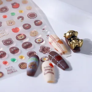 Macro detail of cute 3D bear nail stickers with cookie patterns and gold bear charms
