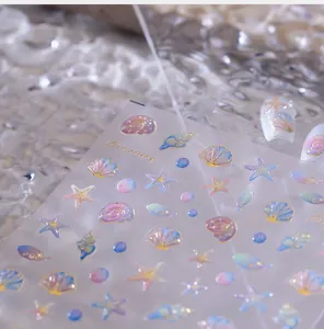 Macro detail of seashell and starfish nail stickers with golden foil edges and gradient color