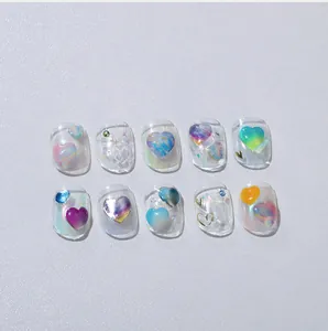 Détail de breloques cœur 3D et finition pailletée aurora sur 10 ongles faits main