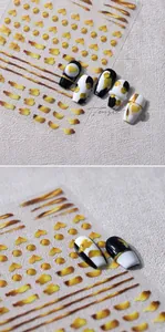 Macro detail of gold metallic nail stickers featuring heart and dot patterns on black nails