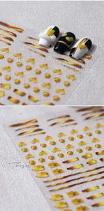 Detailed view of gold heart nail art stickers applied on black and white false nails