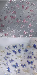 Macro-opname van 3D-vlindernagelstickers met roze glitters en blauw-gouden reliëf