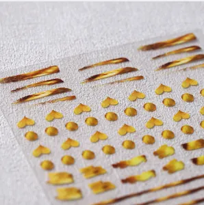 Macro shot of gold heart and dot nail art stickers with metallic texture on clear film