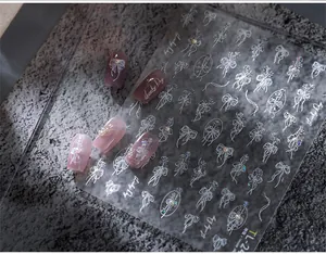 Detailed relief nail stickers featuring white 3D ribbons and floral patterns with pearls