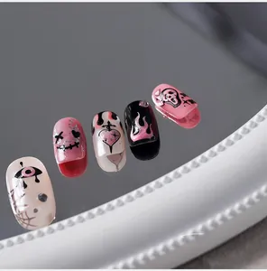 Détail macro de faux ongles gothiques punk avec motifs tête de mort et flammes