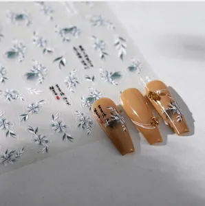 Detailed view of blue floral and calligraphy nail art stickers on long khaki nails