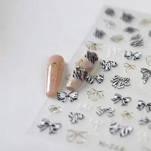 Detail of 3D zebra pattern and golden bow nail art stickers applied on manicured nails