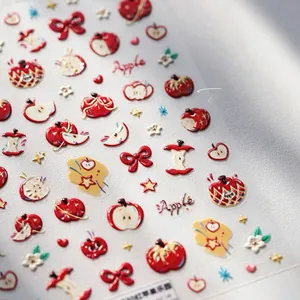 Detail of embossed apple nail stickers with red bows and golden stars for cute DIY manicure