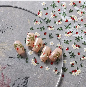 Detailed macro shot of white floral and strawberry nail stickers with 3D texture M-698