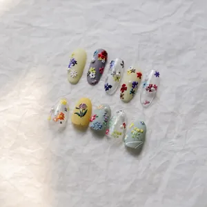 Detail view of 3D embossed floral nail art with pearls and matte finish textures